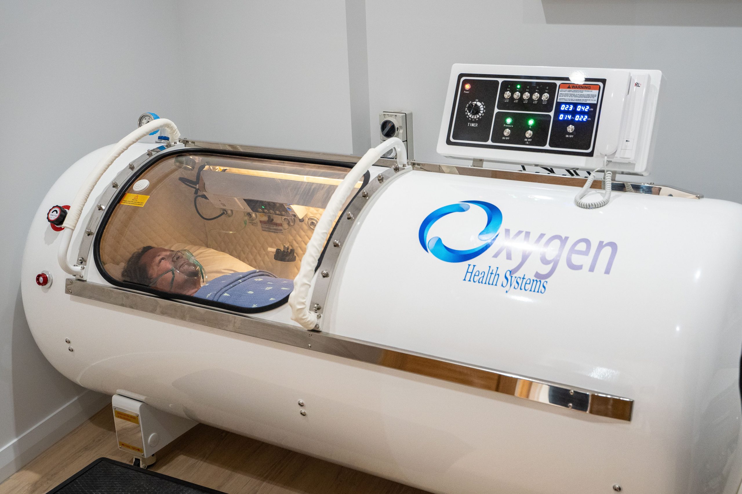 Man undergoing Hyperbaric Oxygen Therapy in hard shell chamber